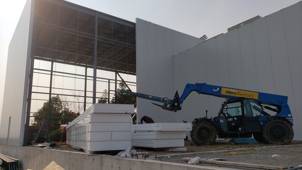 Tractor installing insulated metal panels at ice cream facility